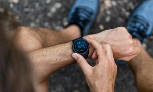 En man som har på sig en svart smartwatch med digitala siffror som lyser