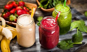 Tre glas med olika smoothies med grönsaker och frukt runt