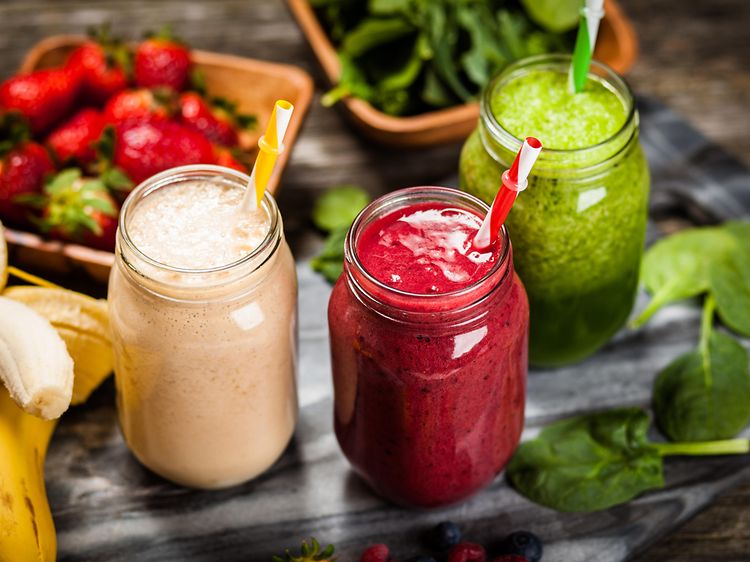 Tre glas med olika smoothies med grönsaker och frukt runt
