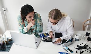 Two women repairing electronics