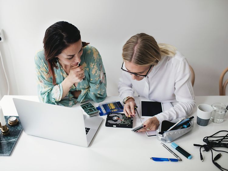 Two women repairing electronics