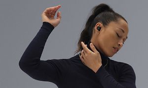 Kvinna med svart tröja och slutna ögon dansar med Momentum TW3 i örat