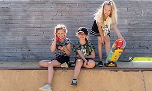 Tre tjejer på en skate-ramp i solen