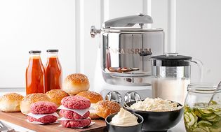 Hamburgerkött, hamburgerbröd och aioli och inlagd gurka, och en Ankarsrum köksmaskin och en mixer i bakgrunden