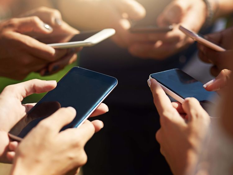 En grupp med människor som använder sina smartphones synkront i dagsljus