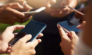 En grupp med människor som använder sina smartphones synkront i dagsljus