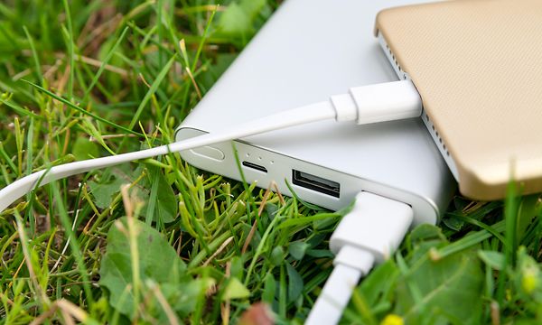 Powerbank laddar en smartphone i gräset