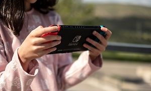 A little girl is holding a Nintendo Switch