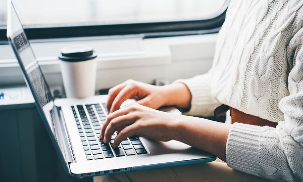 Close-up on a laptop and a woman using it on a train