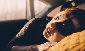 A woman is sleeping in a car with a sleep mask