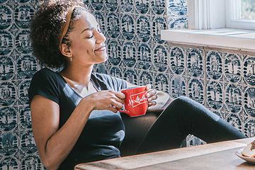 Kvinna som dricker från en kaffekopp och en kaffemaskin står på ett bord.