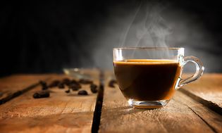 Fråga oss om kaffe: En rykande kopp kaffe på ett träbord.