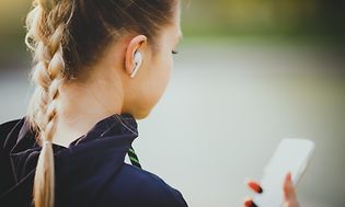 Brown goods -Earbuds - Woman checking phone-min