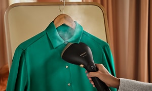 Person som steamar en grön skjorta med Philips Steamer 7000