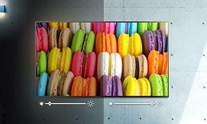 Färgglada macaroner på en skärm som är delad i en blekare och en väldigt klar del och illustrerad brightness-inställning under