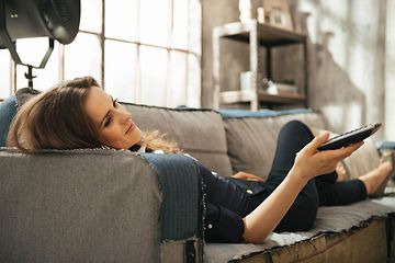 Relaxed woman lying on sofa and watching tv