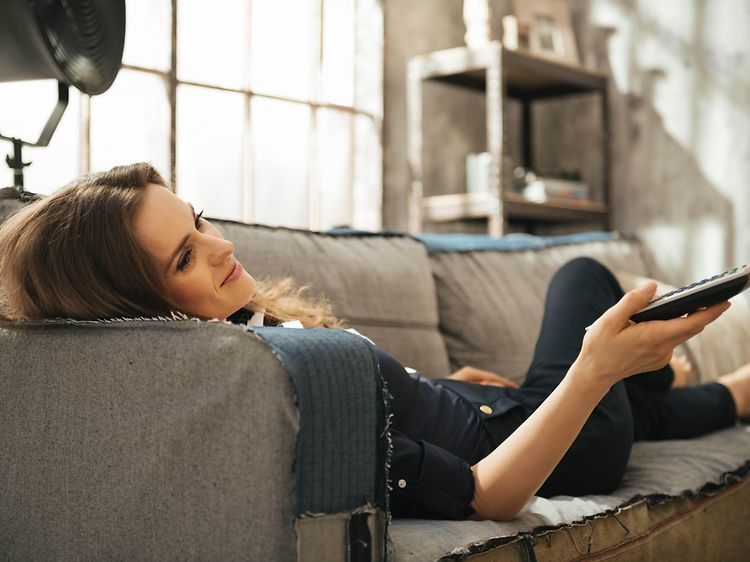 Relaxed woman lying on sofa and watching tv