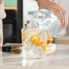 Person som häller kolsyrat vatten i ett glas