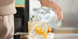 Person som häller kolsyrat vatten i ett glas