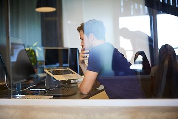 Man som sitter på ett kontor vid ett skrivbord med datorer framför sig och ser ut att fundera