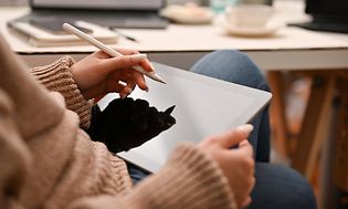 Computing-Woman holding a white pen over a tablet