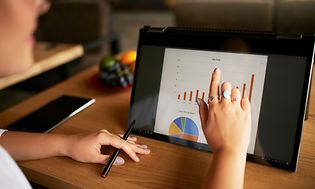 Computing-Finger touching the chart over convertible laptop screen in tent mode