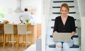 Kvinna sitter i trappa och skriver på sin dator
