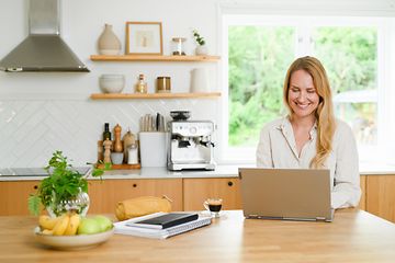 Kvinna använder bärbar dator i kök