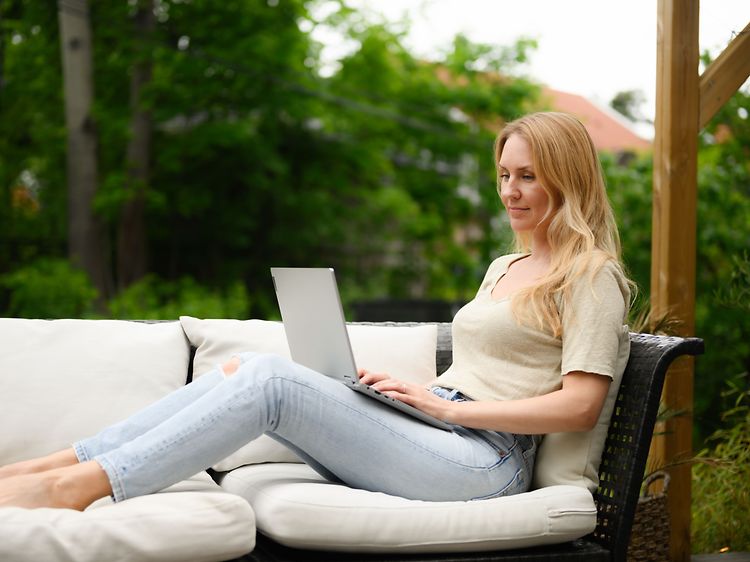Kvinna använder bärbar dator på altan