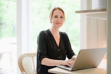 Kvinna jobbar på sin dator vid ett bord