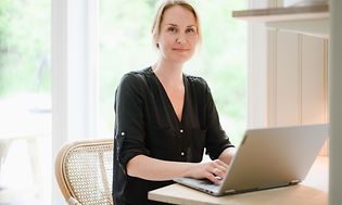 Kvinna jobbar på sin dator vid ett bord