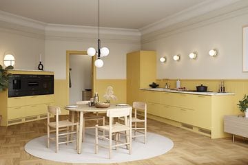 Öppet gult Epoq-kök med ett runt matbord på en ljus matta i mitten.