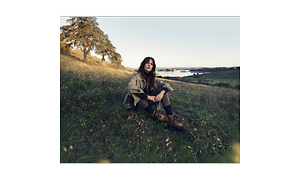 Woman sitting on a grass field looking at us