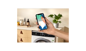 Hand holding a smartphone in front of a Electrolux washing machine (1)