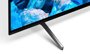 Sony-A75K Närbild av TV-stativ och ett hörn av en TV-skärm som visar blå ädelstenar