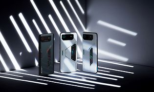 Tre olika ROG phone 6 serier står i ett mörkt rum med ljusstrimmor som lyser på dem