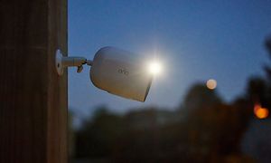 Arlo Go V2 övervakningskamera fäst till en vägg utomhus med mörk himmel i bakgrunden