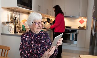 Old lady using her tablet in a kitchen