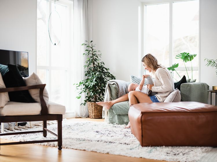 Woman and baby sitting on a couch in the living room