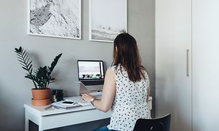 En kvinna arbetar på sin bärbara dator i sitt lilla hemmakontor.