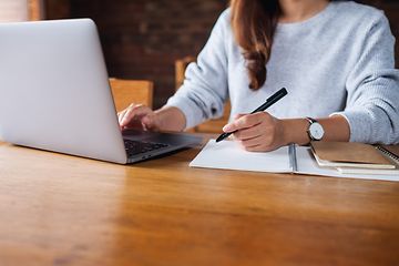 Kvinna på kontor jobbar på sin laptop och skriver i en anteckningsbok