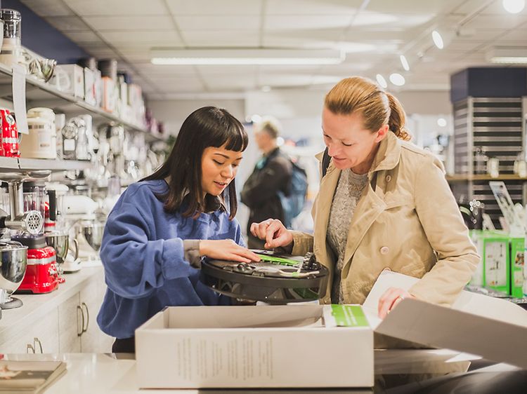 Sustainability - Top image desktop- Two women checking out o robotic vacuum cleane