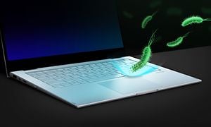 Ett upplyst tangentbord på en Vivobook S14 med illustration av gröna bakterier som faller ovanifrån men stöts bort