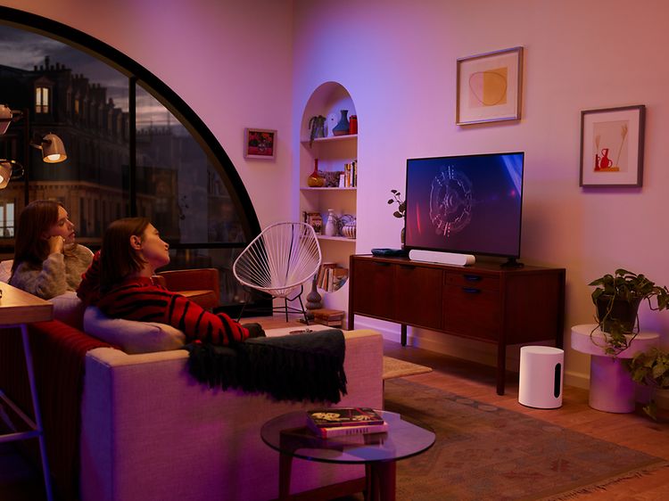 Personer som tittar på TV i ett rum med Gravity Sub på golvet