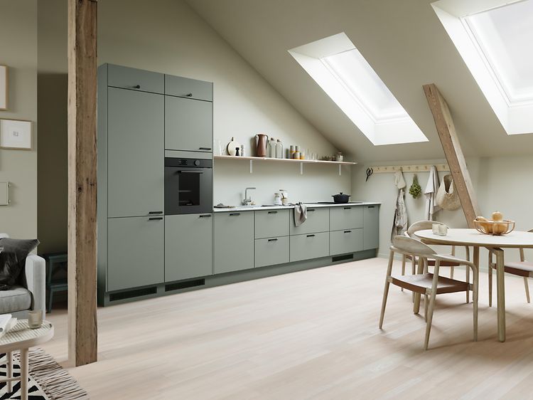 Epoq Trend Sage-kök i en öppen kökslösning med snedtak, inbyggd ugn, dekorhylla och runt matbord av trä med stolar runt