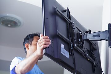 En man monterar en TV på ett väggfäste.
