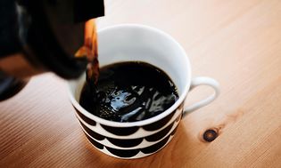 En person häller nykokt kaffe i en kaffekopp från en kaffekanna