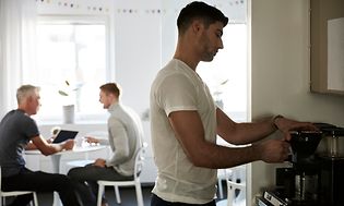 Kontorsarbetare som brygger kaffe i en kaffebryggare på sin arbetsplats