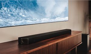 Samsung soundbar på en TV-bänk under en TV-skärm som visar vågigt hav