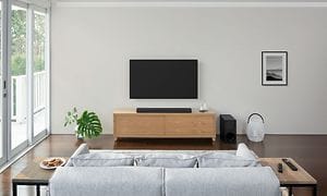 Vardagsrum med en grå soffa och en soundbar under en TV rakt framför den